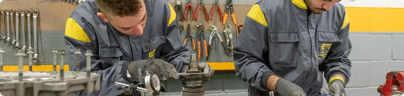 Midiendo pieza de metal de motor con mono de ETG puesto